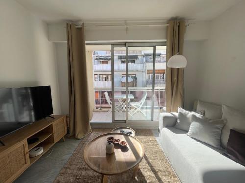 un salon avec un canapé, une table et une télévision dans l'établissement apppartement avec terrasse - 2 à 4 personnes, à Nice