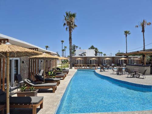 a swimming pool with chaise lounges and chairs next to a resort at Aegean Pearl in Tigaki