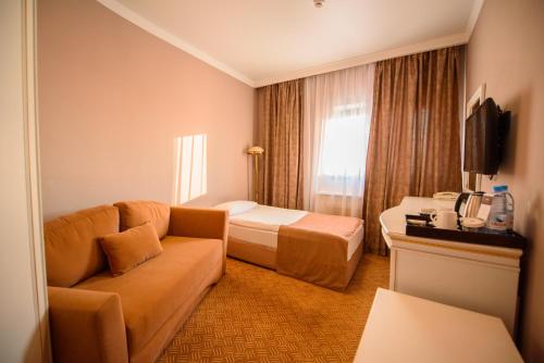 a hotel room with a couch and a bed and a tv at Kazakhstan Express in Almaty