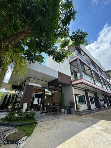 a building with a tree in front of it at Maesai Bliss Residence in Ban Pa Yang