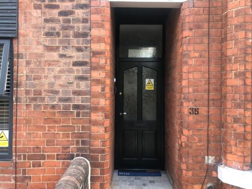 a brick wall with a black door in a brick building at Stylish flat in Chesterfield near Peak District in Chesterfield