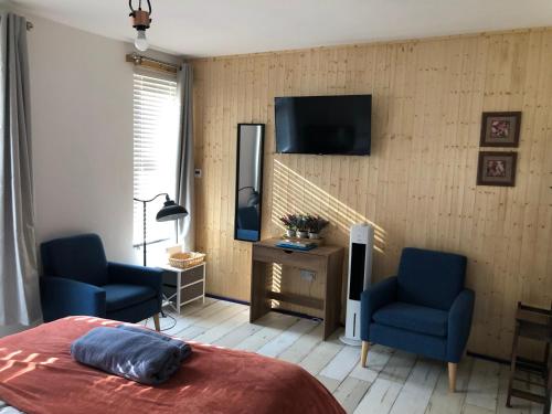 a bedroom with two blue chairs and a tv on the wall at Stylish flat in Chesterfield near Peak District in Chesterfield