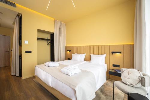 a bedroom with a large white bed with towels on it at Viale Boutique Hotel in Villány
