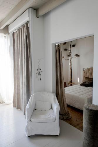 a bedroom with a white chair and a bed at La maison sur la place in Penne-dʼAgenais