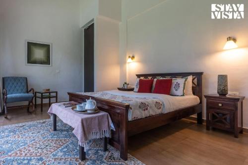 a bedroom with a bed and a table and a chair at StayVista at Samara - 4BR with Pool & River View in Pālghar