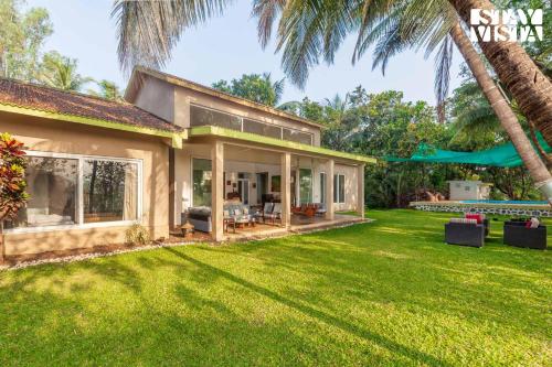 a house with a large yard with palm trees at StayVista at Samara - 4BR with Pool & River View in Pālghar