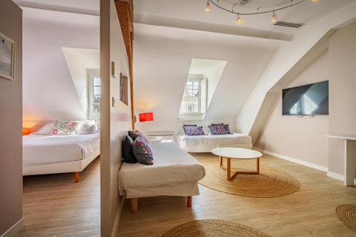 a room with two beds and a couch and a table at The Originals Boutique, Hôtel Le Londres, Saumur in Saumur