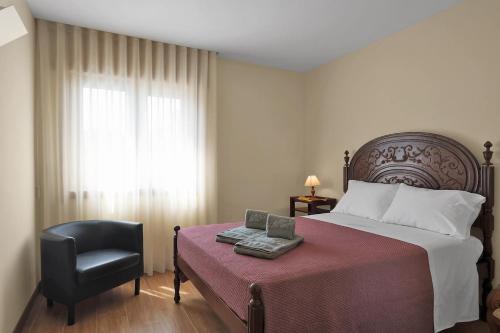 a bedroom with a bed and a chair and a window at Vintage Copio Apartment in Vila Nova de Gaia