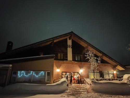 people standing outside a building in the snow at night at Hotel Tae Windsor in Myoko