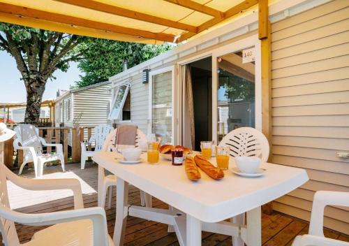 une table blanche et des chaises sur une terrasse dans l'établissement Camping Rivages des Landes - Eurocamp I Homair, à Aureilhan