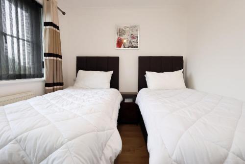 two beds in a room with white sheets at Kites House Long Stays Sleep 8 Free Parking and WI-FI in Bristol