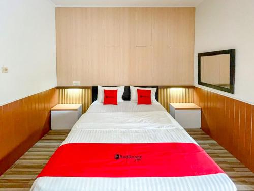 a bedroom with a large bed with red pillows at RedDoorz Syariah Plus near Banyuwangi Airport in Dadapan