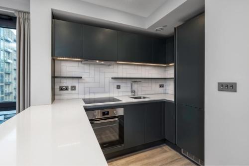 a kitchen with black cabinets and a sink at Alameda and Beton in London near Wembley Park in London