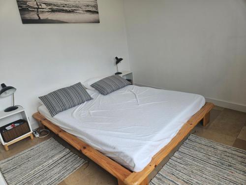 - un lit avec des draps blancs et 2 oreillers dans l'établissement Juan les Pins Front de Mer 2P parking Colombier, à Antibes