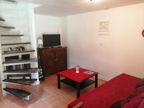 - un salon avec une table rouge et une télévision dans l'établissement Gîte du Moulin de Brendouez, à Guissény