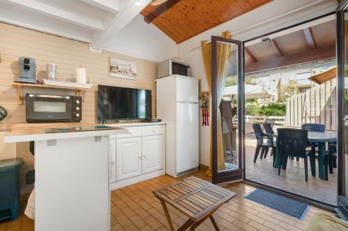 Il comprend une cuisine équipée d'un réfrigérateur et d'une table avec des chaises. dans l'établissement Le Santa-Marina - proche plage, à Fleury