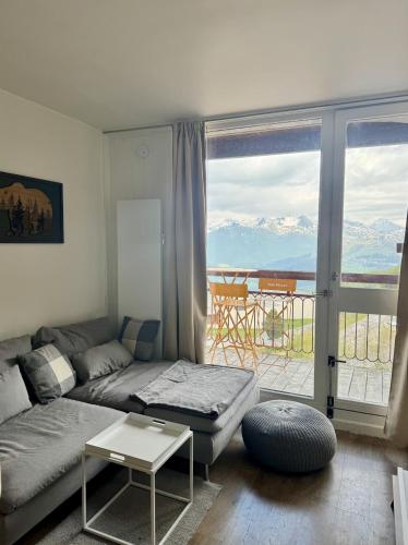 Una sala de estar con un sofá y un balcón. en ARC 2000, Studio rénové 4 couchages, Vue Montagne, en Arc 2000