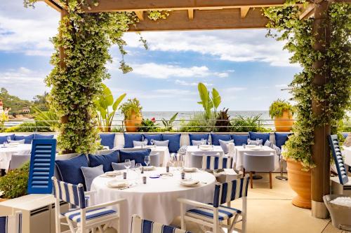 a restaurant with white tables and chairs and a view of the ocean at Monte-Carlo Beach in Roquebrune-Cap-Martin