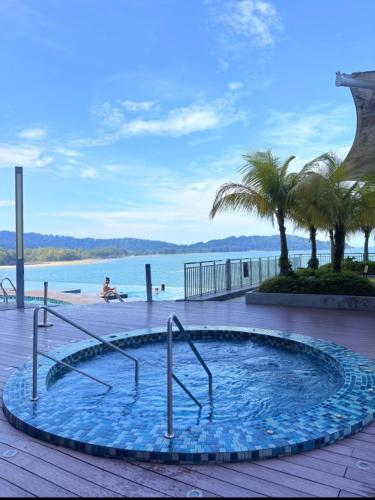 a swimming pool with palm trees and a body of water at Comfy Imperium Residence Kuantan Studio Seaview in Kuantan