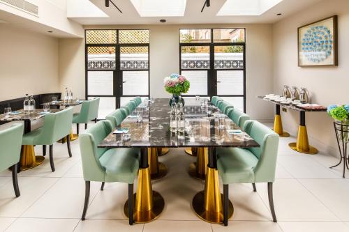 a large dining room with a long table and green chairs at Ellen Kensington in London