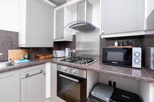 a kitchen with white cabinets and a microwave at Open Mind Property -2 Bedrooms with FREE parking in Bournemouth