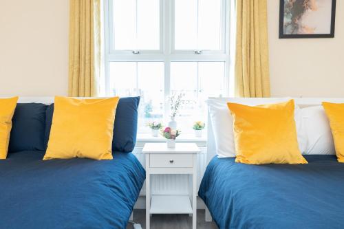 two beds with blue and yellow pillows in a bedroom at Open Mind Property -2 Bedrooms with FREE parking in Bournemouth