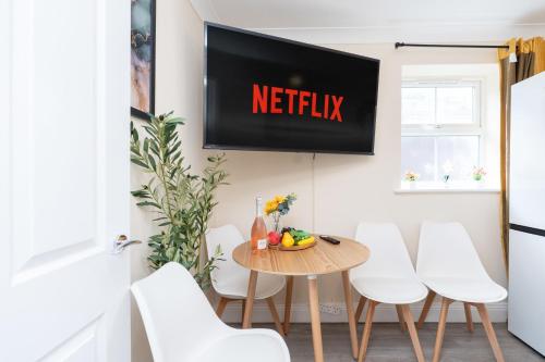 a television hanging on a wall above a dining room table at Open Mind Property -2 Bedrooms with FREE parking in Bournemouth