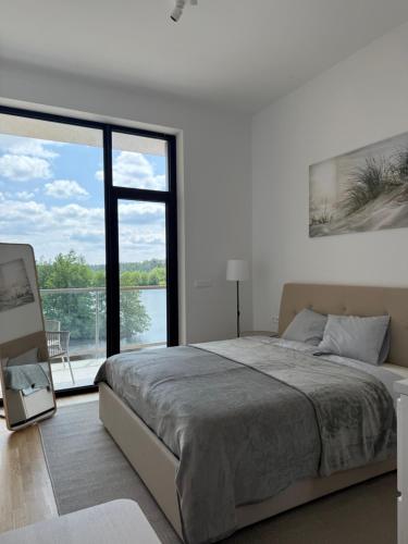 a white bedroom with a bed and a large window at Luxapartments Studio 303 Penati Golf Resort in Šajdíkove Humence