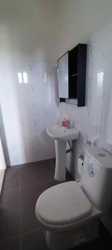 a white bathroom with a toilet and a sink at Affordable Room with Full Kitchen in Calamba in Bukal