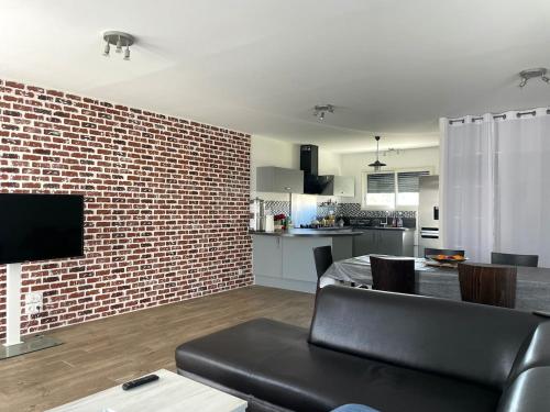 Il dispose d'une cuisine et d'un salon avec un mur en briques. dans l'établissement ღ L'Andillys - Maison Spacieuse, Jardin & Wifi, à La Celle-sous-Gouzon