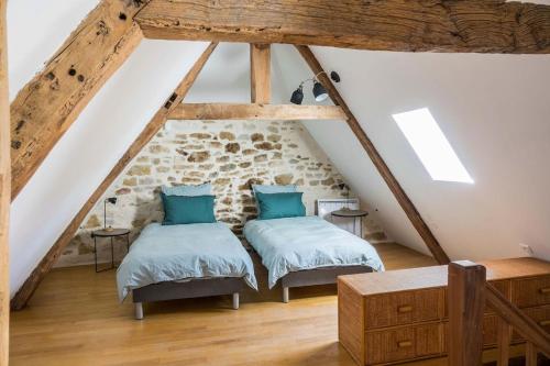 Cette chambre mansardée comprend 2 lits et des poutres apparentes. dans l'établissement Maison de charme Portobelo dans Carennac avec vue, à Carennac