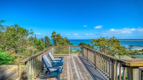 two chairs sitting on a wooden deck overlooking the ocean at Rangi Terrace Views in Karikari Peninsula