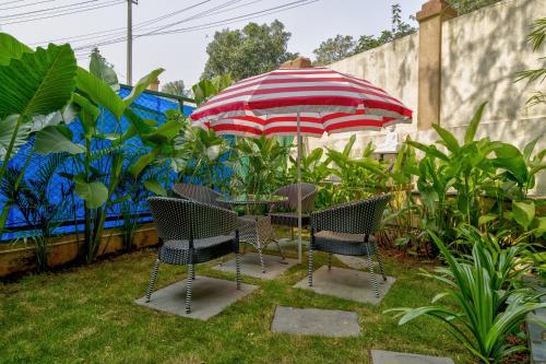 a table and chairs under an umbrella in a yard at Casa Avasa - 3bhk Private Pool Villa in Siolim in Camorlim