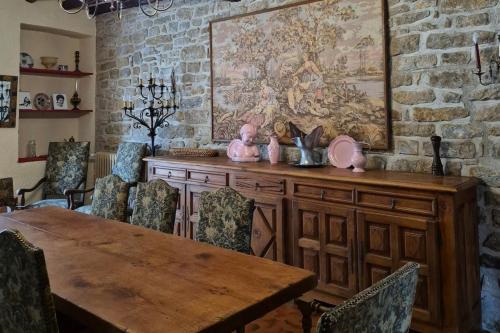 a dining room with a table and a stone wall at Le relais de campagne à 5 min de Padirac in Miers