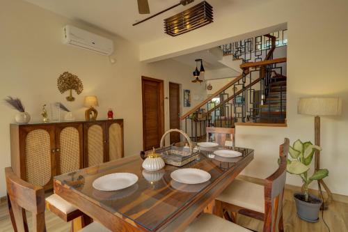 a dining room with a wooden table and chairs at Casa Avasa - 3bhk Private Pool Villa in Siolim in Camorlim