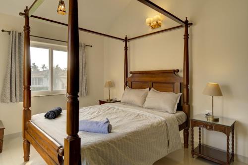 a bedroom with a four poster bed and a window at Casa Avasa - 3bhk Private Pool Villa in Siolim in Camorlim