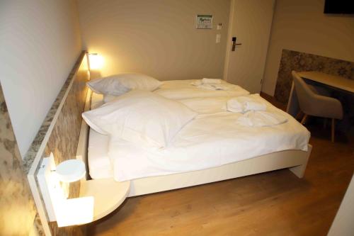 a large white bed in a room with a table at Pension Villa Colosseo im Herzen von Meiningen in Meiningen