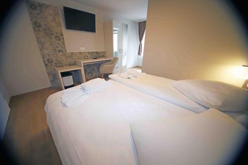 a bedroom with a white bed with a tv on the wall at Pension Villa Colosseo im Herzen von Meiningen in Meiningen