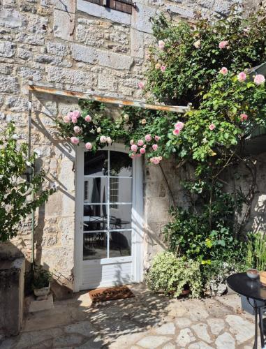 a white door with pink roses on a stone building at Chez Mamie Gramat centre in Gramat