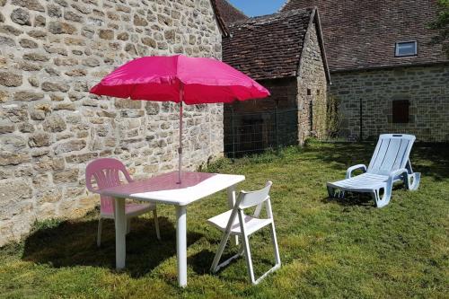 a picnic table with a pink umbrella and two chairs at Charmante maisonnette entre Padirac et Rocamadour in Miers