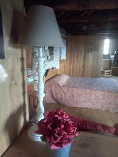 - une chambre avec un lit et une table avec une lampe et des fleurs dans l'établissement La Magnanerie du Serre, à Saint-Hilaire-de-Lavit