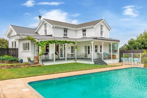 a white house with a swimming pool in front of it at Welcome to Blue Morning house! - Remuera 5 bedrooms villa in Auckland