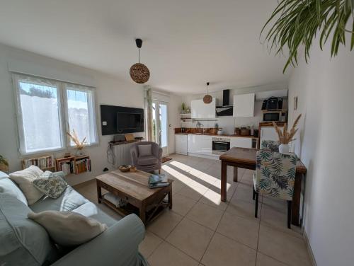 a living room with a couch and a table at Loctycaz Appartement avec jardin in Locmariaquer