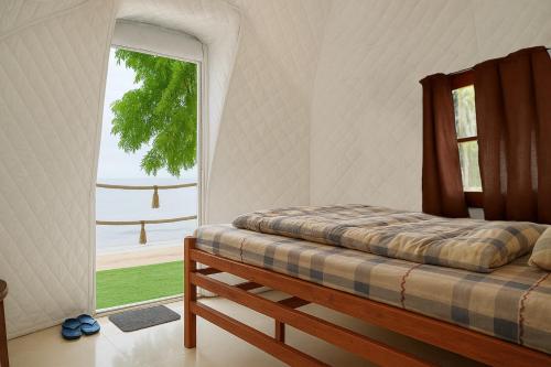 a bedroom with a bed and a large window at Vietnam Surf Camp in Ấp Mỹ Hải