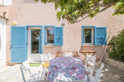 une table et des chaises devant une maison dotée de fenêtres bleues dans l'établissement T4 Marine Sant'ambroggio, à Lumio