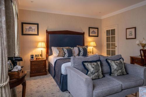 a bedroom with a large bed and a couch at Lucknam Park Hotel in Chippenham