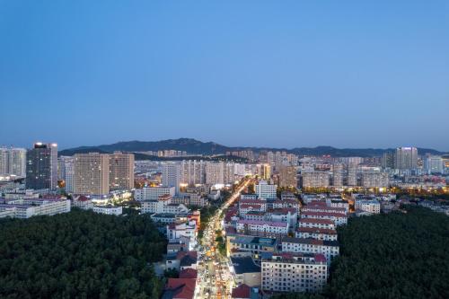 a city at night with buildings and trees at 沃德酒店威海国际海水浴场火炬八街店 in Weihai