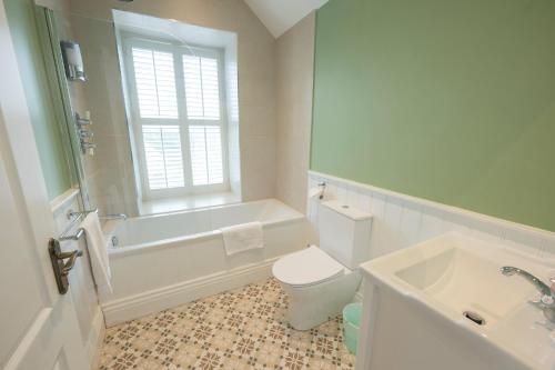 a bathroom with a toilet and a tub and a sink at Tobervilla Guest House in Caherdaniel