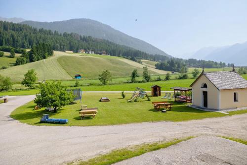 a park with a playground with a house and benches at Untersinnerhof Gsies in Valle Di Casies