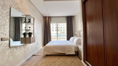 une chambre avec un lit, un miroir et une fenêtre dans l'établissement N8 appartement, 3 Chambres Haut de Gamme, a Deux Pas de l Ocean et du Mall, à Rabat